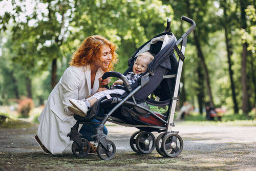 Mother with her little son in a baby carriage in park