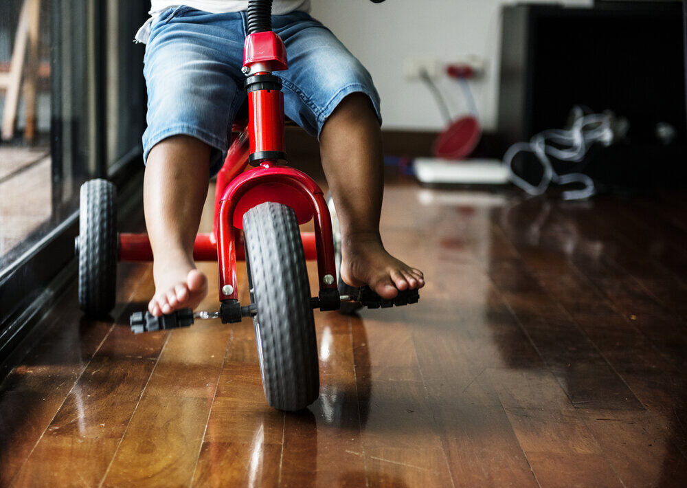 Black kid riding the bike in the house