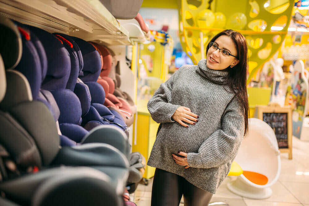 Tehotná žena si vyberá detskú autosedačku v obchode