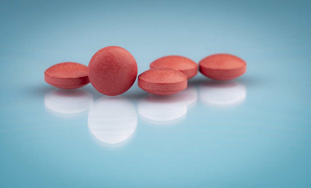 Farmaceutické výrobky. Vitamíny a doplnky. Červené tablety na sivom pozadí.