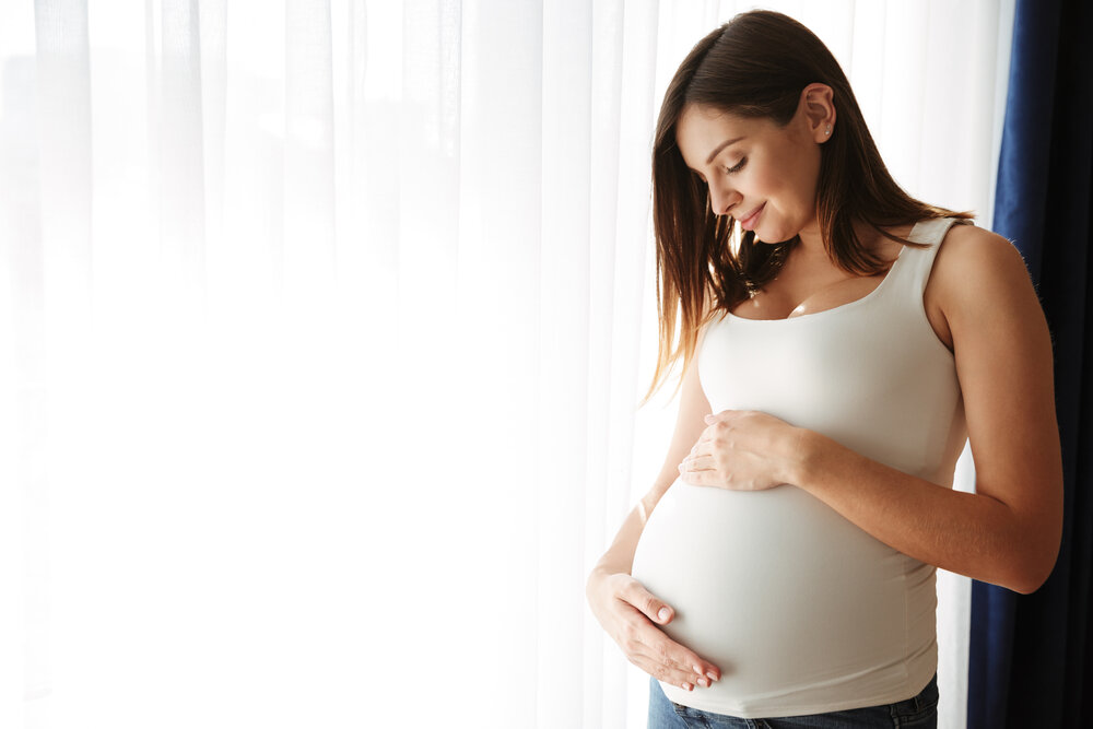 Portrét šťastnej tehotnej ženy dotýkajúcej sa bruška