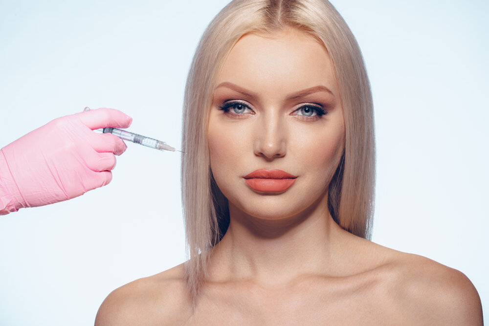 Portrét mladej ženy dostávajúcej injekciu do tváre