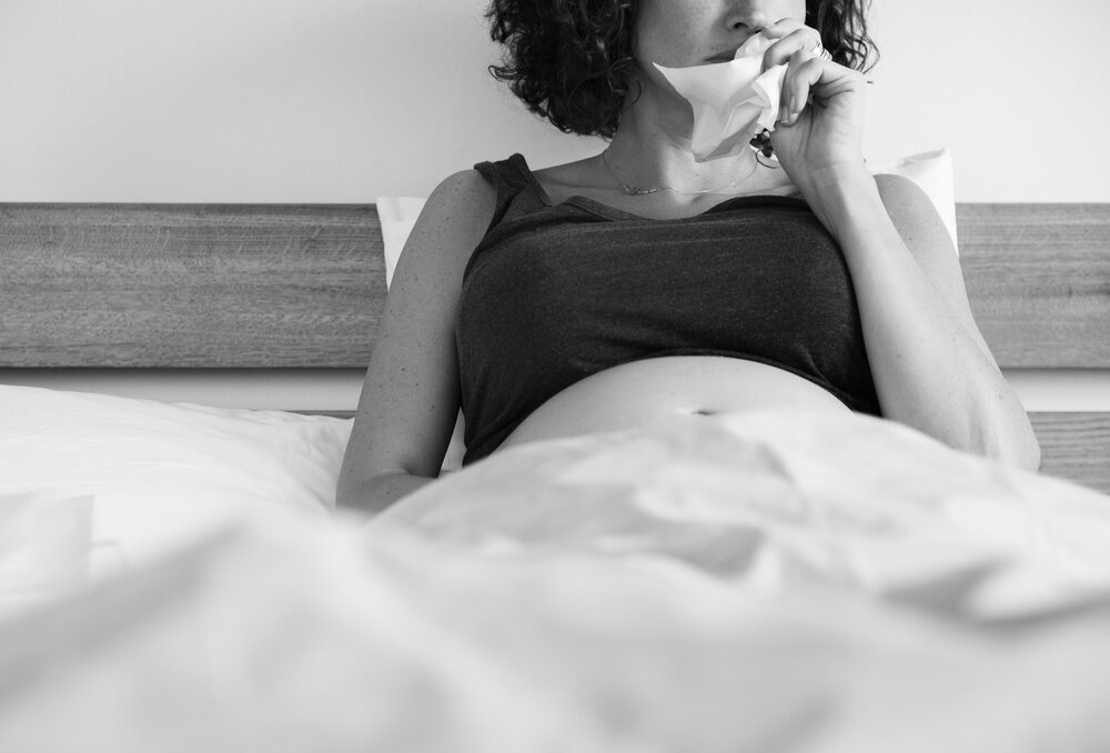 Chorá tehotná žena v posteli