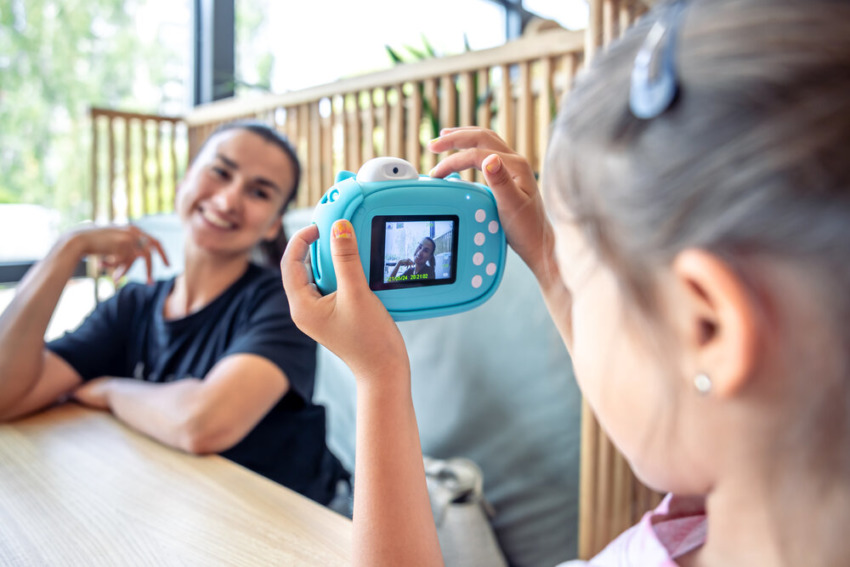 Malé dievčatko fotí svoju matku hračkárskym digitálnym fotoaparátom.