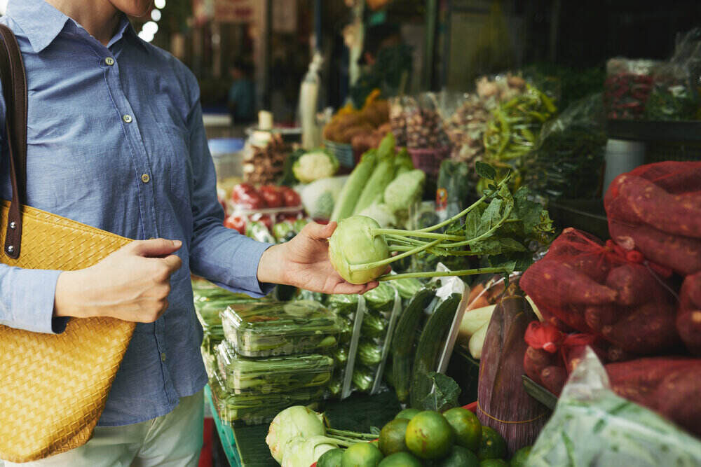Ruky ženy nakupujúcej čerstvý organický kaleráb na trhu s potravinami