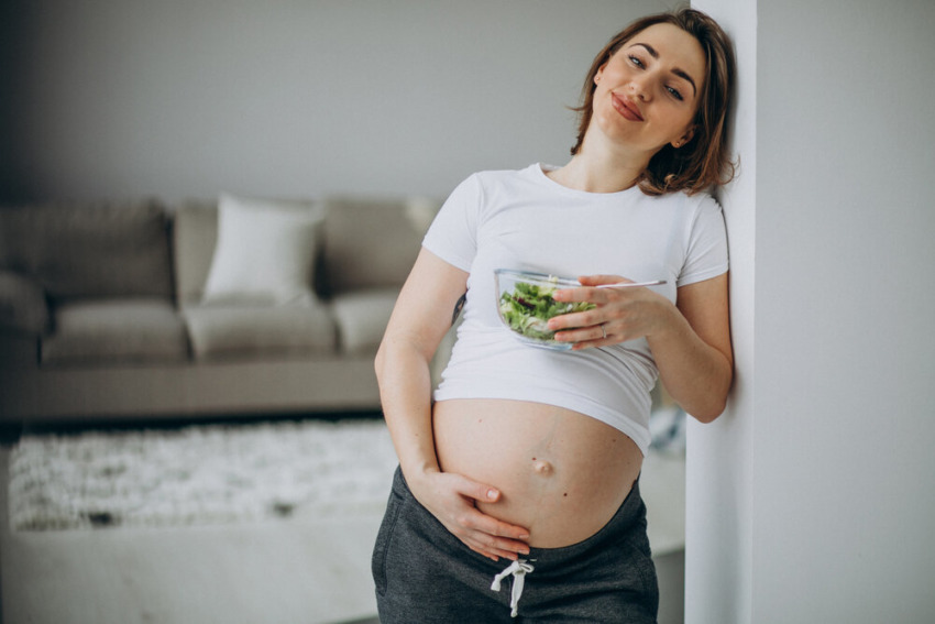 Mladá tehotná žena je šalát . Koncept zdravého stravovania v tehotenstve.