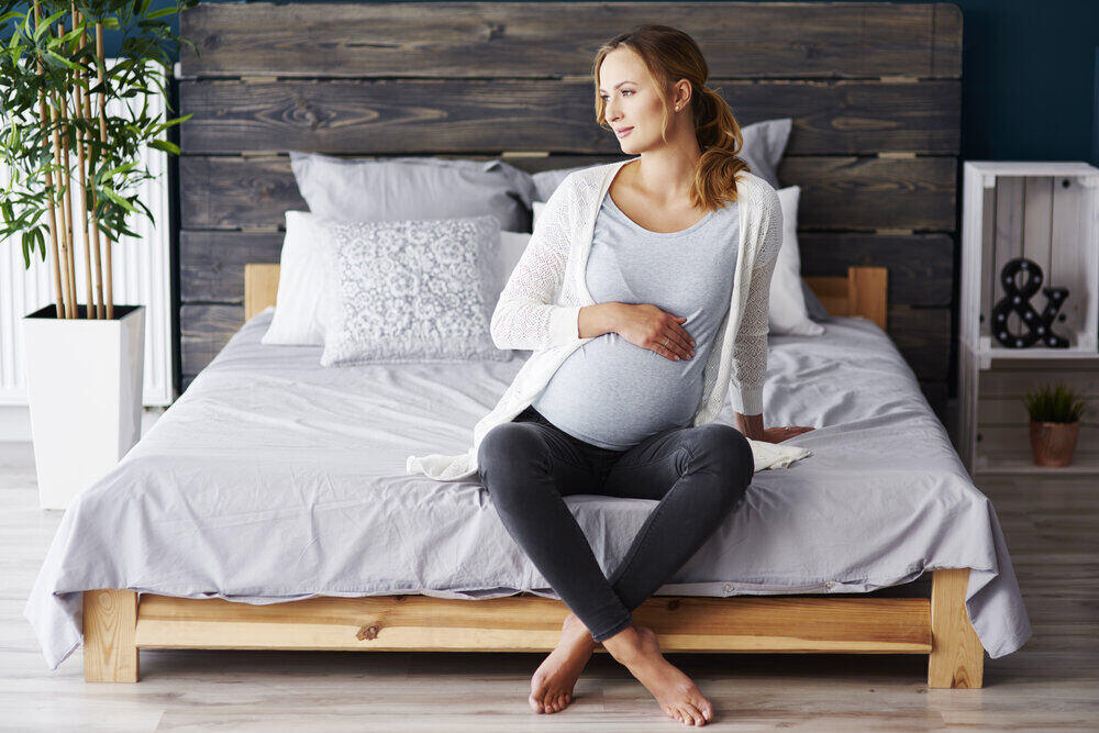 Portrét tehotnej ženy, ktorá odpočíva v spálni