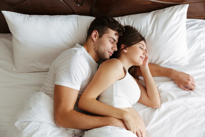 Tehotná žena spí v posteli so svojím manželom