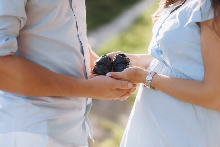 Muž a tehotná žena držia topánky pre novorodenca