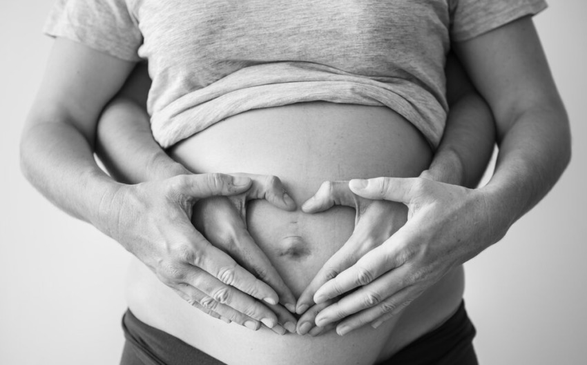 Tehotná žena s manželom na fotení, držiac rastúce bruško budúcej mamičky